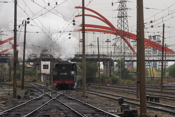 An SY-class steam locomotive running tender-first leads a passenger train into the station at Hegang, China.