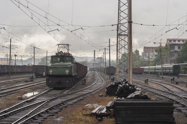 The yard in front of the passenger station in Hegang, China, with an electric locomotive switching coal cars.