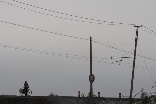 A man on a bicycle crosses the track of the Hegang Coal Mining Railway.