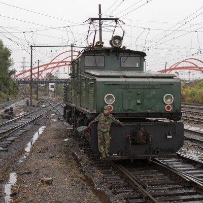 Switchman guides an electric locomotive into the yard in front of the Hegang passenger station.