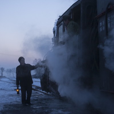 A worker on the Huanan Forestry Railway delivers a message to the crew of a loaded coal train heading west out of Xiahua at twilight on November 28, 2005.