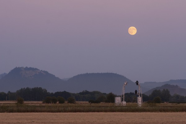 The full moon rises over former Southern Pacific searchlight signals north of Shedd, Oregon, on August 15, 2008.