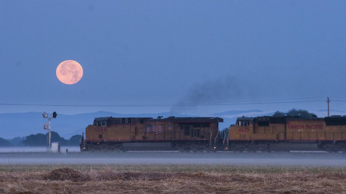 Union Pacific's Portland to Roseville freight train heads south in Oregon's Willamette Valley as the full moon sets at dawn on July 18, 2008.