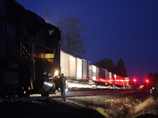 The conductor of a Union Pacific freight train south gives a visual "roll-by" inspection to an intermodal train north at Marion, Oregon, early in the morning of February 11, 2009.