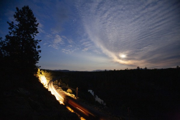 The moon shines through thin clouds about the Williamson River near Kirk, Oregon, as a Union Pacific freight train heads south in the wee hours of July 7, 2009.