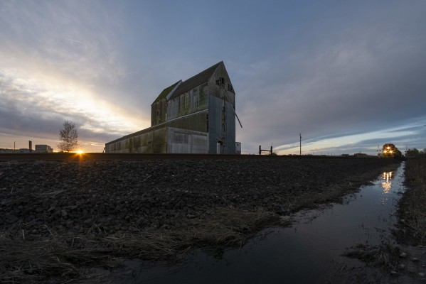 Portland and Western's Westsider freight train heads north past the aging wood elevator at Independence, Oregon, as the sun rises on March 18, 2016.