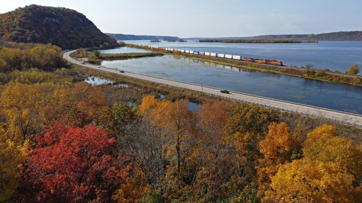 With fall colors near the their peak, a BNSF Railway intermodal train rolls west up Lake Winneshiek in the Mississippi River near Lynxville, Wisconsin, on October 11, 2020.