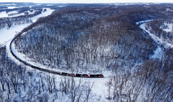 An eastward Canadian National train swings away from the frozen Mississippi River to follow the Galena River at Galena Junction, Illinois. When the Illinois Central Railroad built this line in the 1850s, its locating engineers employed nearly a full half-circle of track at 8.5 degrees of curvature to connect the route between the two valleys. The grade here is just 0.3 percent, but east of Galena, it ramps up to 0.8 percent for eight miles to climb out of the Upper Mississippi Valley.

This shot had been high on my list ever since getting a drone more than a year ago. Summer foliage hides too much of the scene, so a winter view was necessary, but the short days and infrequent trains on this line make it challenging. I snowshoed into this spot from the Casper Bluff Preserve (1.5 miles each way) on two consecutive afternoons. There were no CN trains on the first day, but the second day offered up this one in the late afternoon.