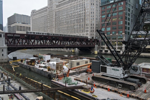 Brown Line train crossing the Chicago River amidst heavy construction work on the riverfront.