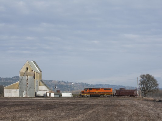Portland and Western 2313 leads a former Southern Pacific caboose north past a grain elevator near Independence, Oregon, on the Westside District on February 16, 2009.