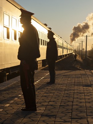 Two Jitong Railway workers stand at attention as the morning passenger train stops at the station at Yamenmiao, Inner Mongolia, China, on an October 2005 morning.