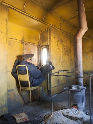 The conductor of a westbound Jitong Railway freight train relaxes in his caboose during the run from Lindong to Daban in November 2005.