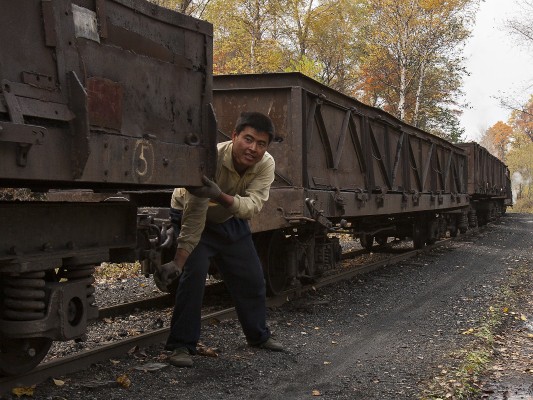 A worker of the Huanan Forestry Railway cranks down handbrakes of loaded coal cars at the summit for the steep descent into Tuoyaozi.