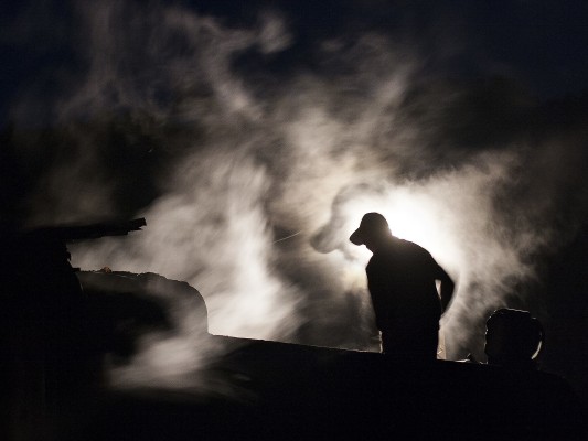 A fireman trims coal in the tender of an 0-8-0 C2 steam locomotive of the Huanan Forestry Railway at the helper station of Lixin before sunrise on September 29, 2005.