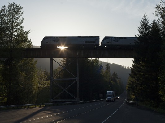 Amtrak's southbound <i>Coast Starlight</i> passenger train no. 11 crosses state highway 58 and Salt Creek during its climb into the Oregon Cascades as the sun sets on May 24, 2009.