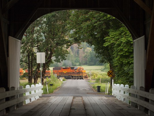 Framed by a covered bridge over the Marys River, Portland and Western's Toledo Hauler freight train rolls through Harris, Oregon, just before sunset on June 29, 2008.