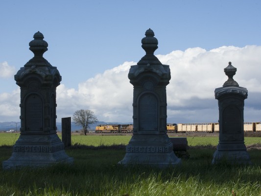Union Pacific Railroad mixed freight train south passing three gravestones in the Independent Order of Odd Fellows cemetery near Harrisburg, Oregon, on February 27, 2010.