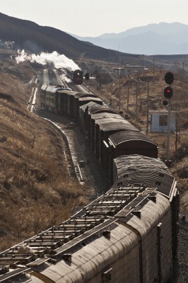 Westbound, diesel-powered freight train meeting an eastbound, steam-powered passenger special at the summit of Jingpeng Pass in November 2005.