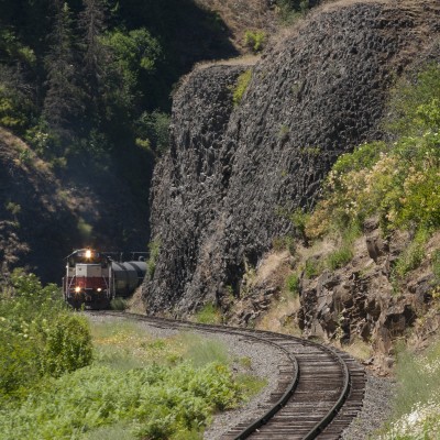 In July 2005, St. Maries River Railroad's outbound Clarkia Logger passes basalt cliffs near milepost 14 of the branch line extending south from St. Maries, Idaho, up the railroad's namesake river.