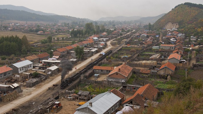 An eight-car empty coal train of the Huanan Forestry Railway steams through the village of Tuoyaozi, Heilongjiang, China, on September 29, 2005.